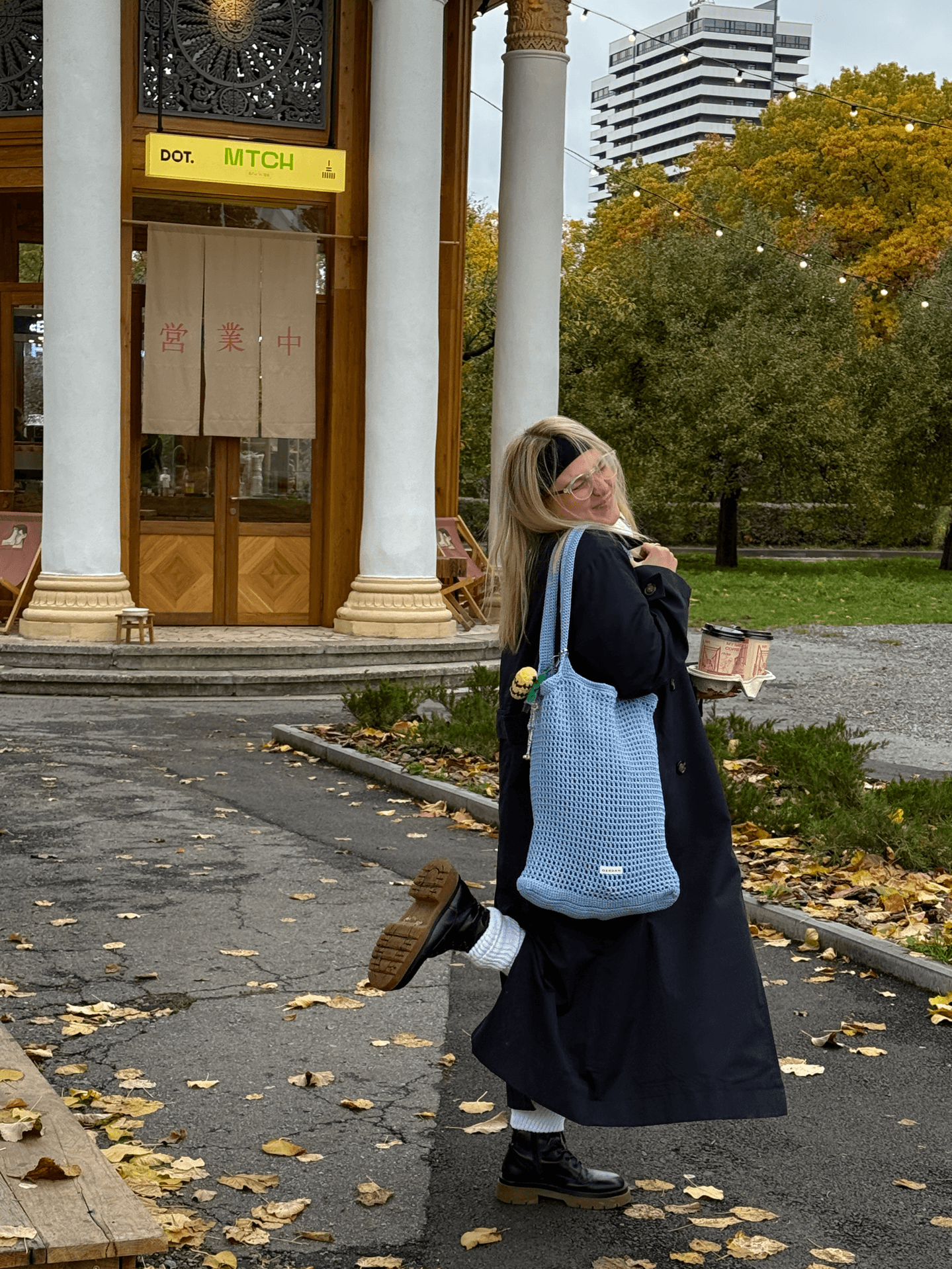 Дівчина тримає блакитний шопер на фоні осіннього парку